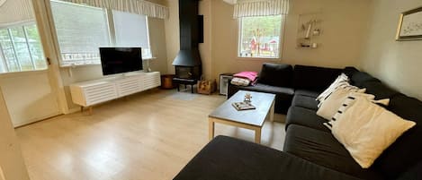 A living room with a black sofa, a coffee table, a fireplace, and a television on a white stand.