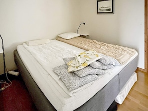 A neatly made bed with a white and gray duvet, a pillow, and a folded blanket with a floral pattern. - 4 Star Holiday Home in Yngsjo, Sverige (Yngsjo)