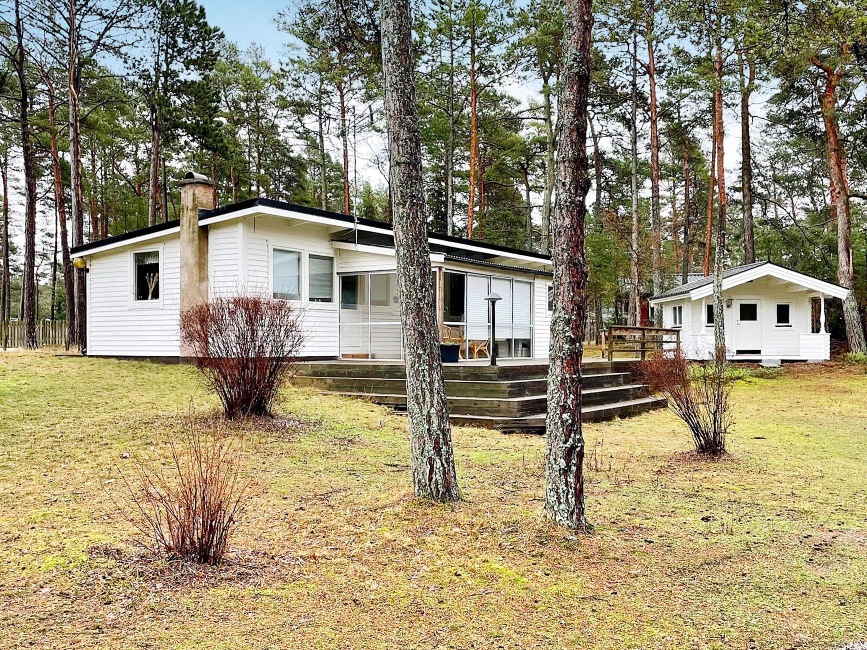 A cabin with a porch and steps leading up to the entrance, surrounded by trees.