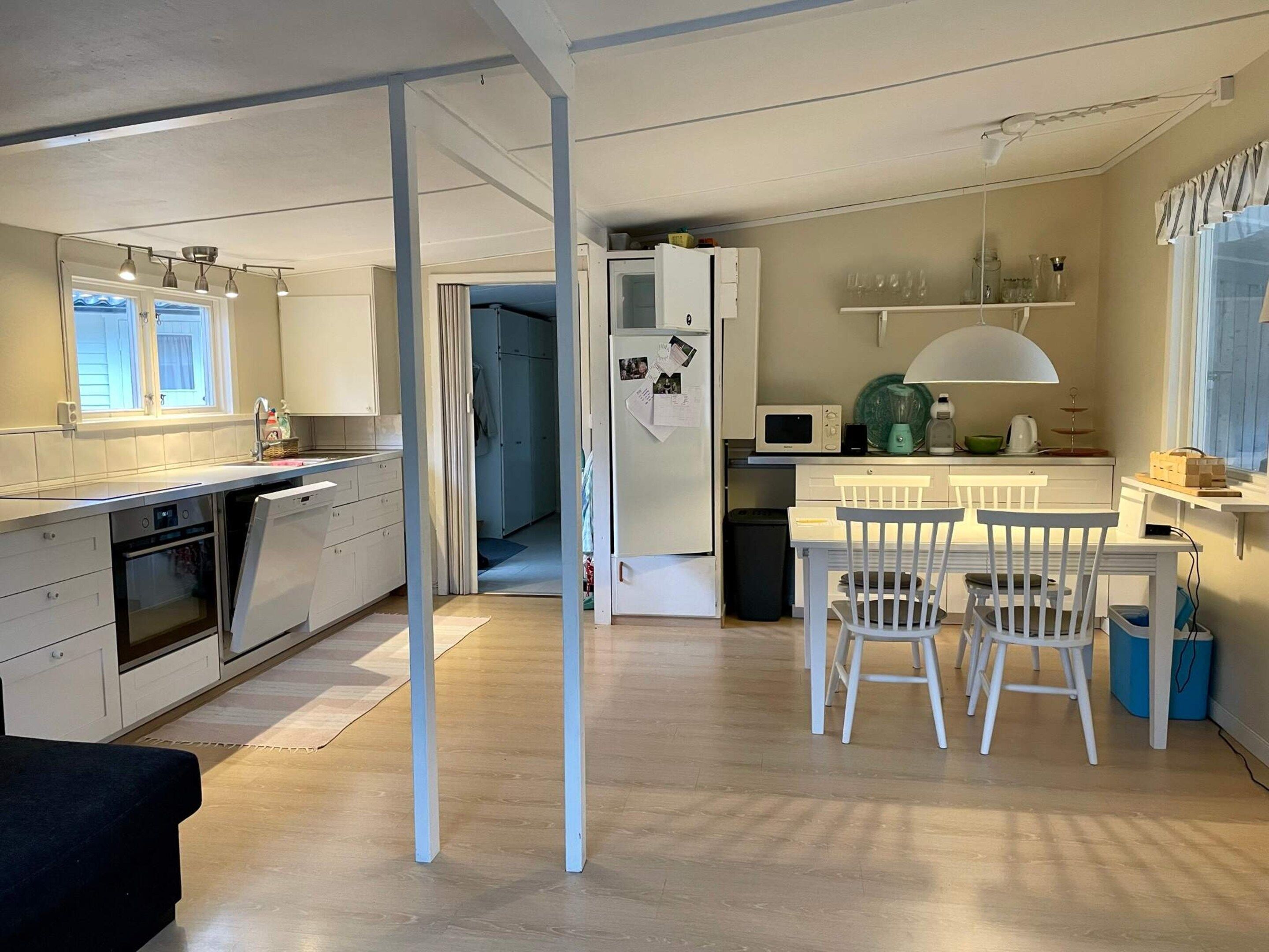 A compact kitchen with a microwave, a sink, and a dining area with chairs.