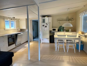 A compact kitchen with a microwave, a sink, and a dining area with chairs.