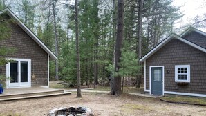 Two cabins with a fire pit in the center, surrounded by a forest. - Torch Lake Cabin near launch with boat option (Rapid City)