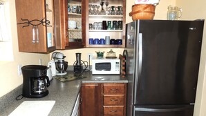 Una cocina con refrigerador de acero inoxidable, cafetera, microondas y armarios de madera.