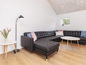 Una sala de estar moderna con un sofá modular, una mesa de centro redonda y una lámpara de pie.