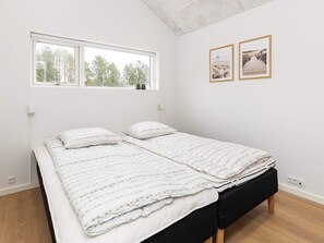 Un dormitorio con cama, ventana y dos cuadros en la pared.