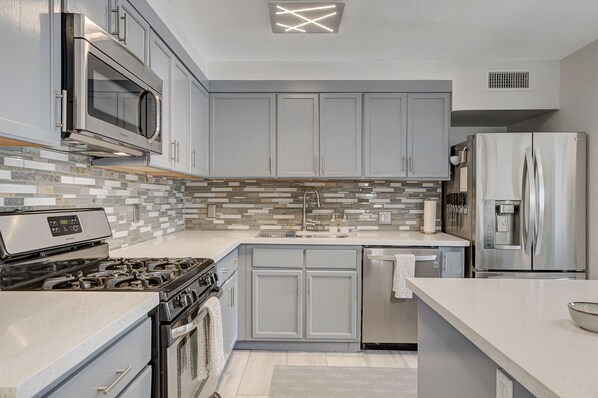 Enjoy cooking in this well-equipped kitchen with a range hood, microwave, refrigerator, sink, and dishwasher.