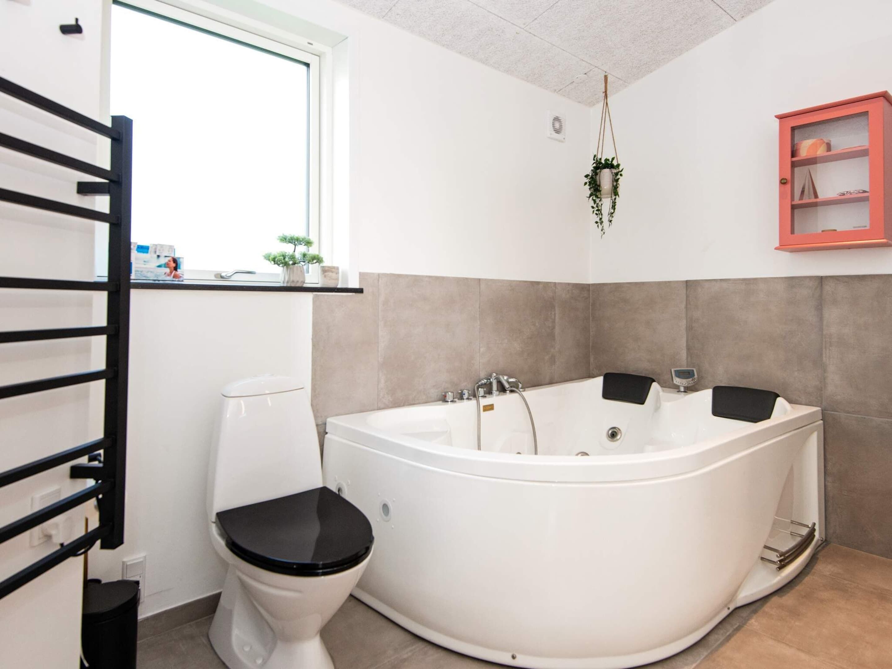 A bathroom with a white bathtub, a toilet, and a window.