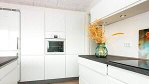 A modern kitchen with white cabinetry, a built-in oven, and a black countertop. - 10 Person Holiday Home in Bjert (Bjert)