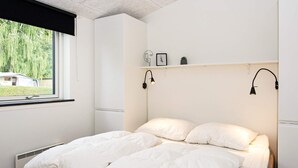A bedroom with a bed, a window, a shelf with decorative items, and wall-mounted lights. - 10 Person Holiday Home in Bjert (Bjert)