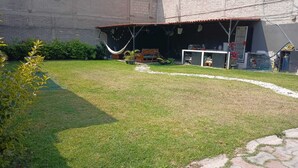 A backyard with a hammock, a covered seating area, and a small garden.
