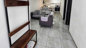 A modern interior with a sofa set, a wooden bench with hooks, and a tiled floor.