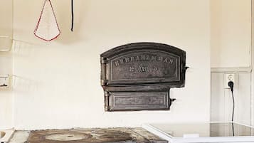 A kitchen with a vintage stove, a hanging kitchen towel, and a wall-mounted electrical outlet.