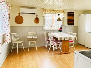 Een keuken met een eettafel, stoelen, een koelkast en een raam met gordijnen.