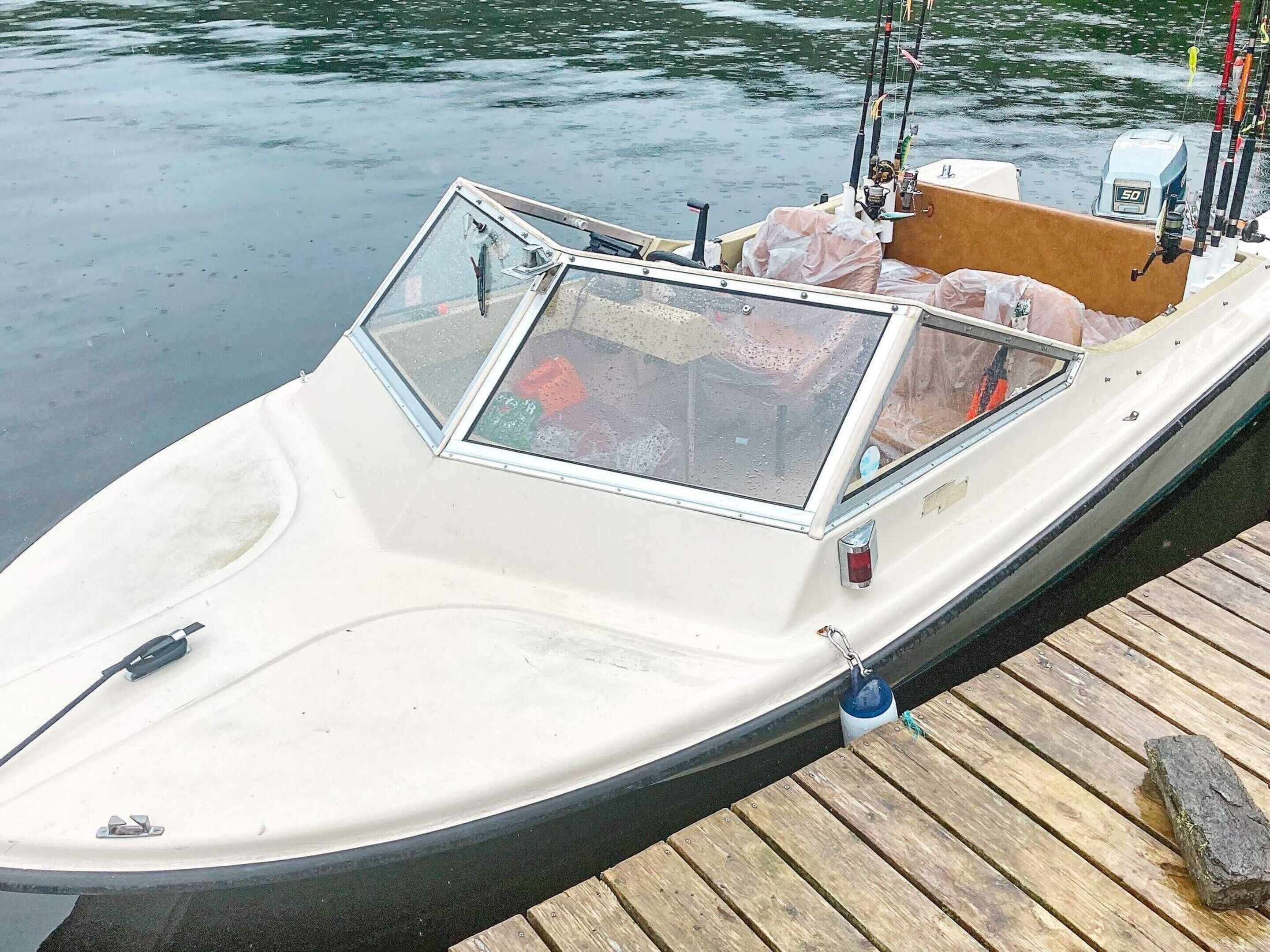 A small, white boat docked at a wooden pier.