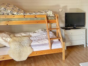A bunk bed with a wooden ladder, a television on a stand, and a white dresser in a room with wooden flooring. - 10 Person Holiday Home in Halden (Halden)