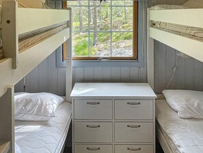 A dormitory room with bunk beds, a desk, and a window with a view of trees. - 10 Person Holiday Home in Halden (Halden)