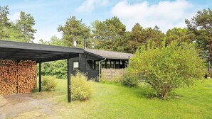 Een rustieke hut met een overdekte veranda en een houtstapel.