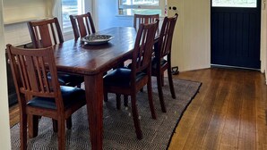 A dining room with a wooden table and chairs, a chandelier, and a view through a door. - A charming cottage with picturesque rural views over surrounding rural farm land (Melville Forest)