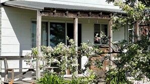 A house with a covered porch, a chimney, and a garden with flowering plants. - A charming cottage with picturesque rural views over surrounding rural farm land (Melville Forest)