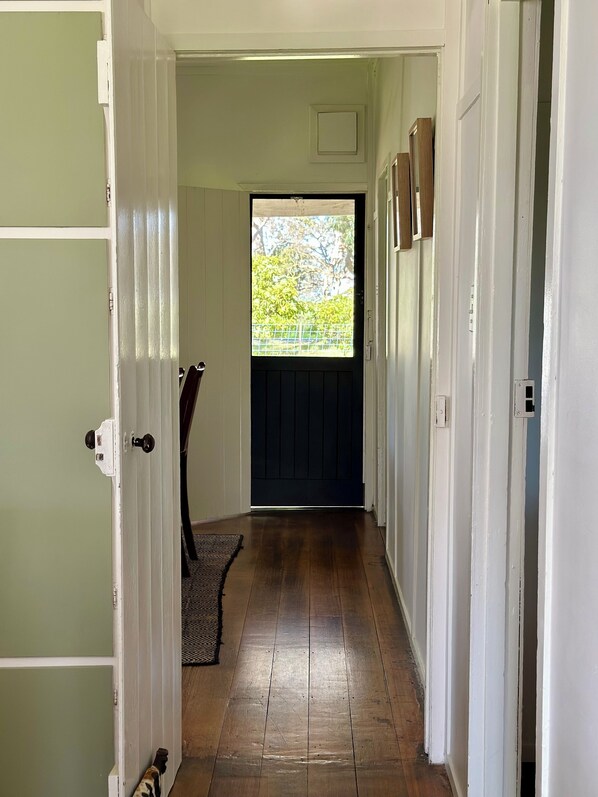 A hallway with a wooden floor, a door with a white frame, and a window with a view of greenery. - A charming cottage with picturesque rural views over surrounding rural farm land (Melville Forest)