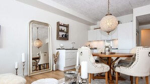 Een moderne woonkamer met een glazen salontafel, witte meubels en een kroonluchter.