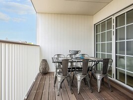 Un balcone con tavolo e sedie, un'ampia finestra e un vaso decorativo.