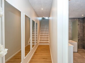 A modern interior with a wooden staircase, white walls, and a shower area.