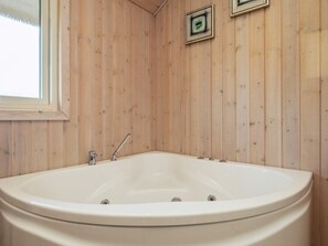 A wooden-paneled bathroom with a freestanding bathtub, a window, and two framed pictures on the wall. - 8 Person Holiday Home in Brovst (Brovst)