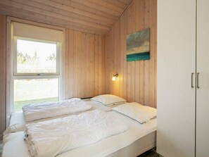 A room with two beds, a window, a wall-mounted light, and a painting.