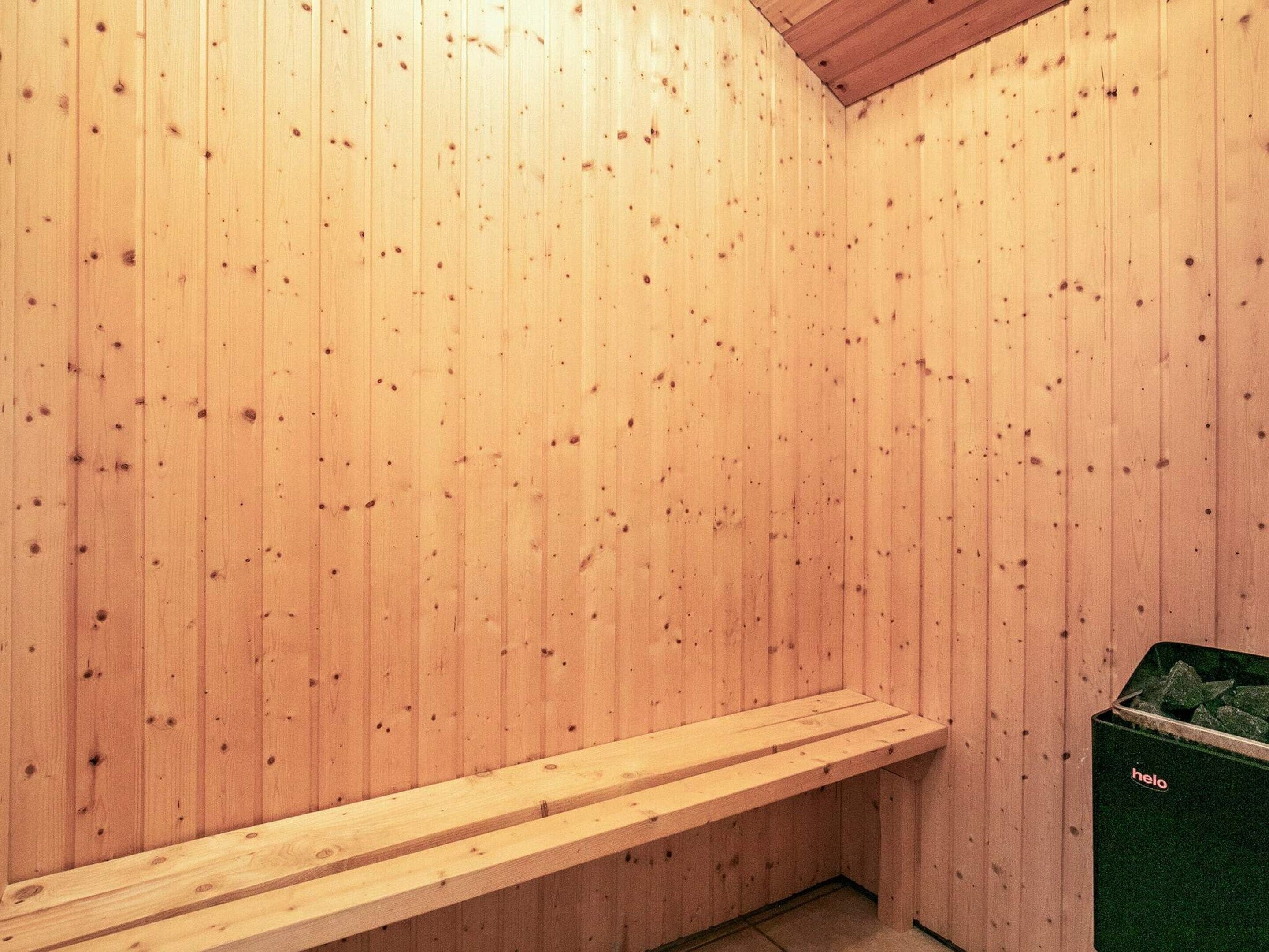A sauna room with wooden walls and a bench.