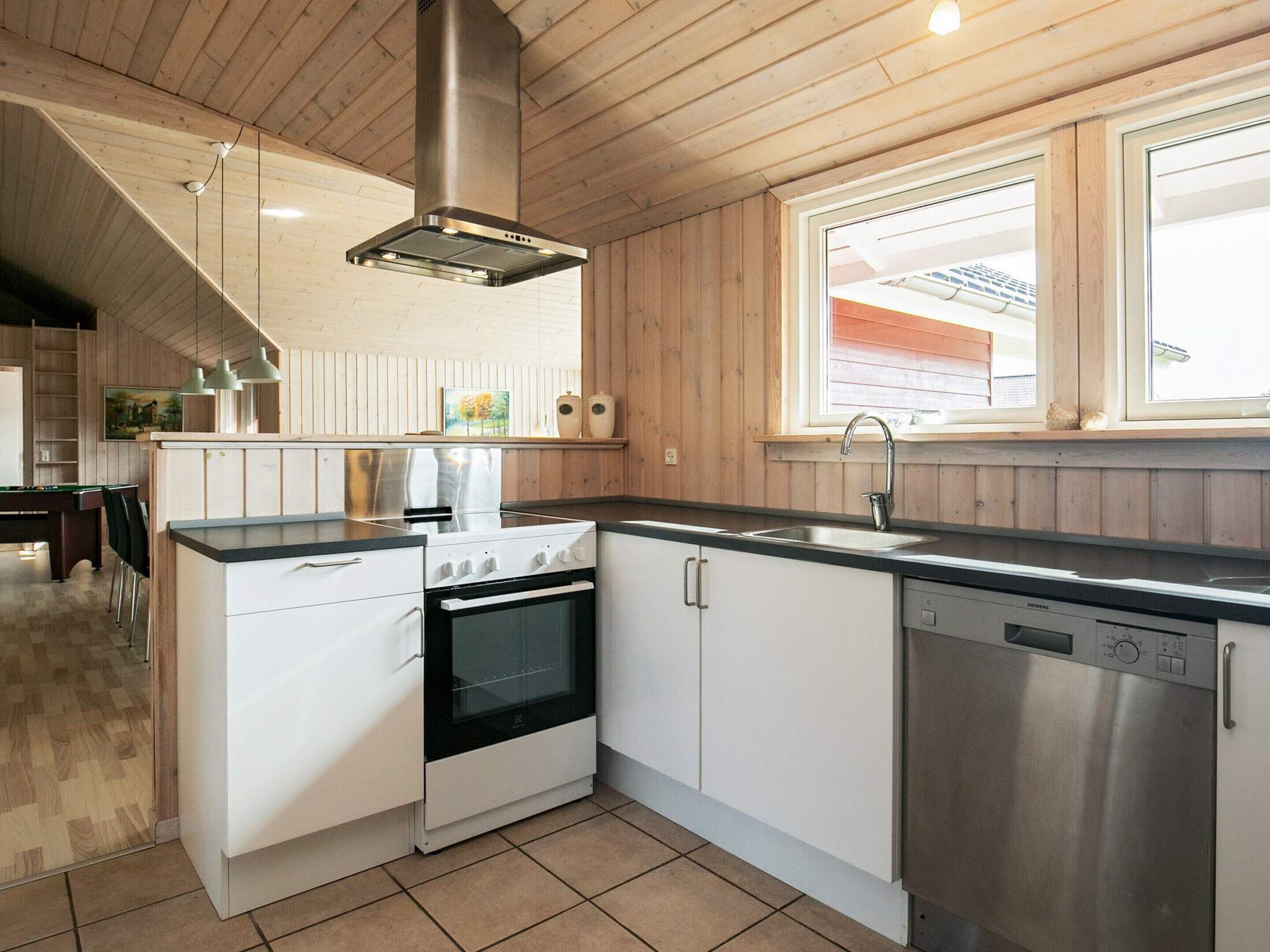 Une cuisine équipée d’une cuisinière, d’un four, d’un lave-vaisselle et d’une fenêtre située au-dessus de l’évier.