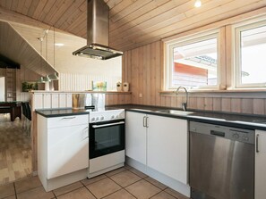 A kitchen with a stove, oven, dishwasher, and a window above the sink.