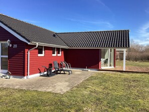 A red building with a tiled roof, a covered patio with chairs, and a number '28' on the side.