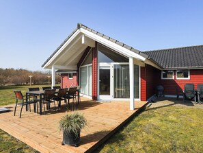A red building with a covered patio area, a sliding glass door, and a small window. - 8 Person Holiday Home in Brovst (Brovst)