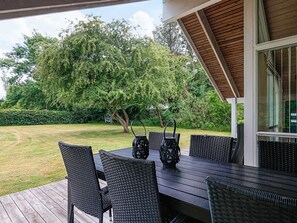 An outdoor patio with a table and chairs, surrounded by greenery and trees. - 4 Star Holiday Home in Asaa (Asaa)