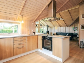 A modern kitchen with wooden cabinetry, a central island, and a built-in oven.