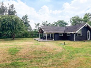 A two-story house with a covered patio area and a lawn. - 4 Star Holiday Home in Asaa (Asaa)