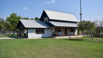 A single-story house with a sloped metal roof, a front porch, and a small attached garage.