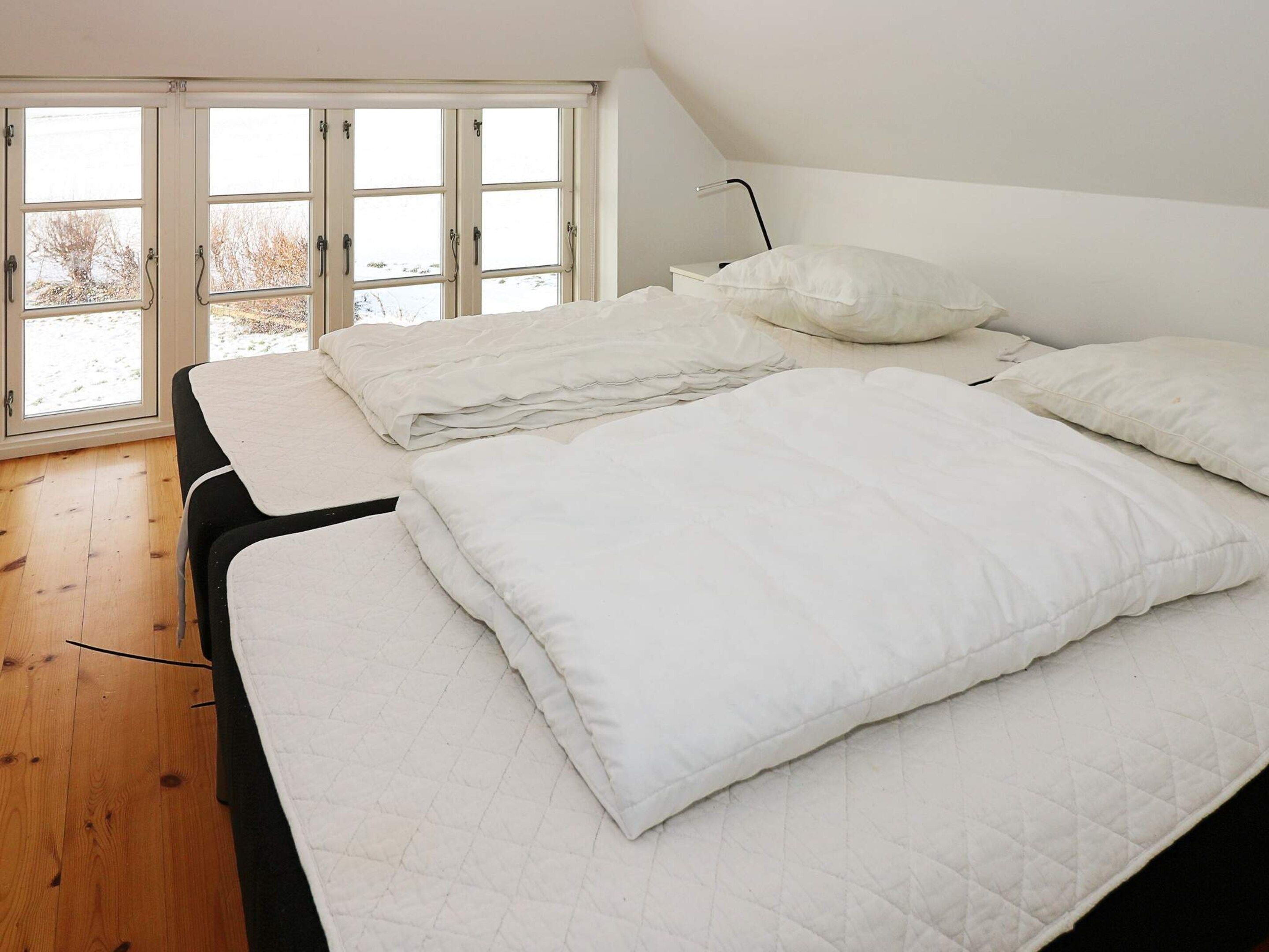 A bedroom with a bed, pillows, and a window with a view of the outdoors.