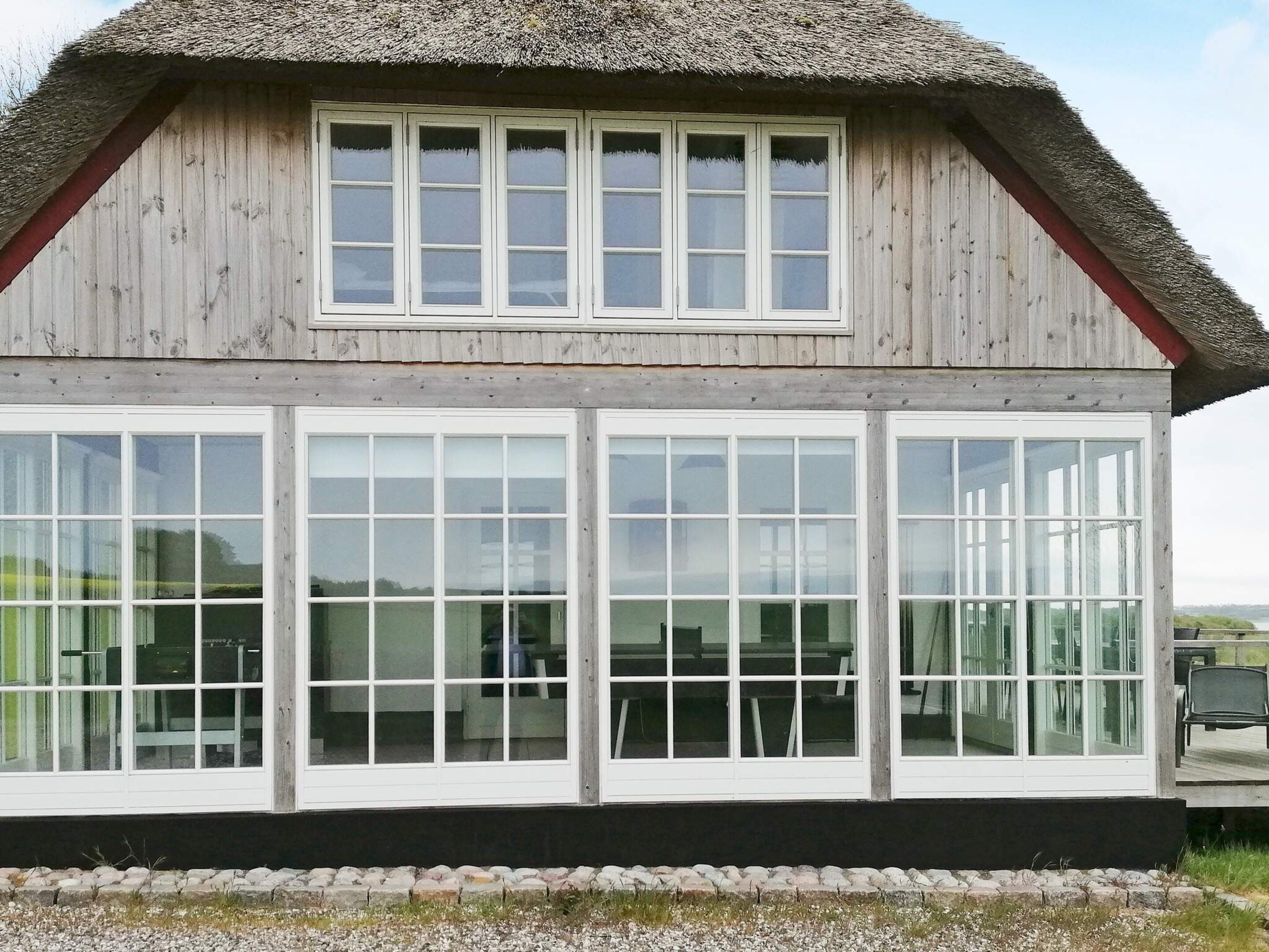 Een houten gebouw met rieten dak en grote ramen.