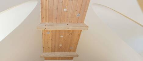 A wooden slatted ceiling with a central beam and a lower horizontal beam, likely part of a room's architecture.