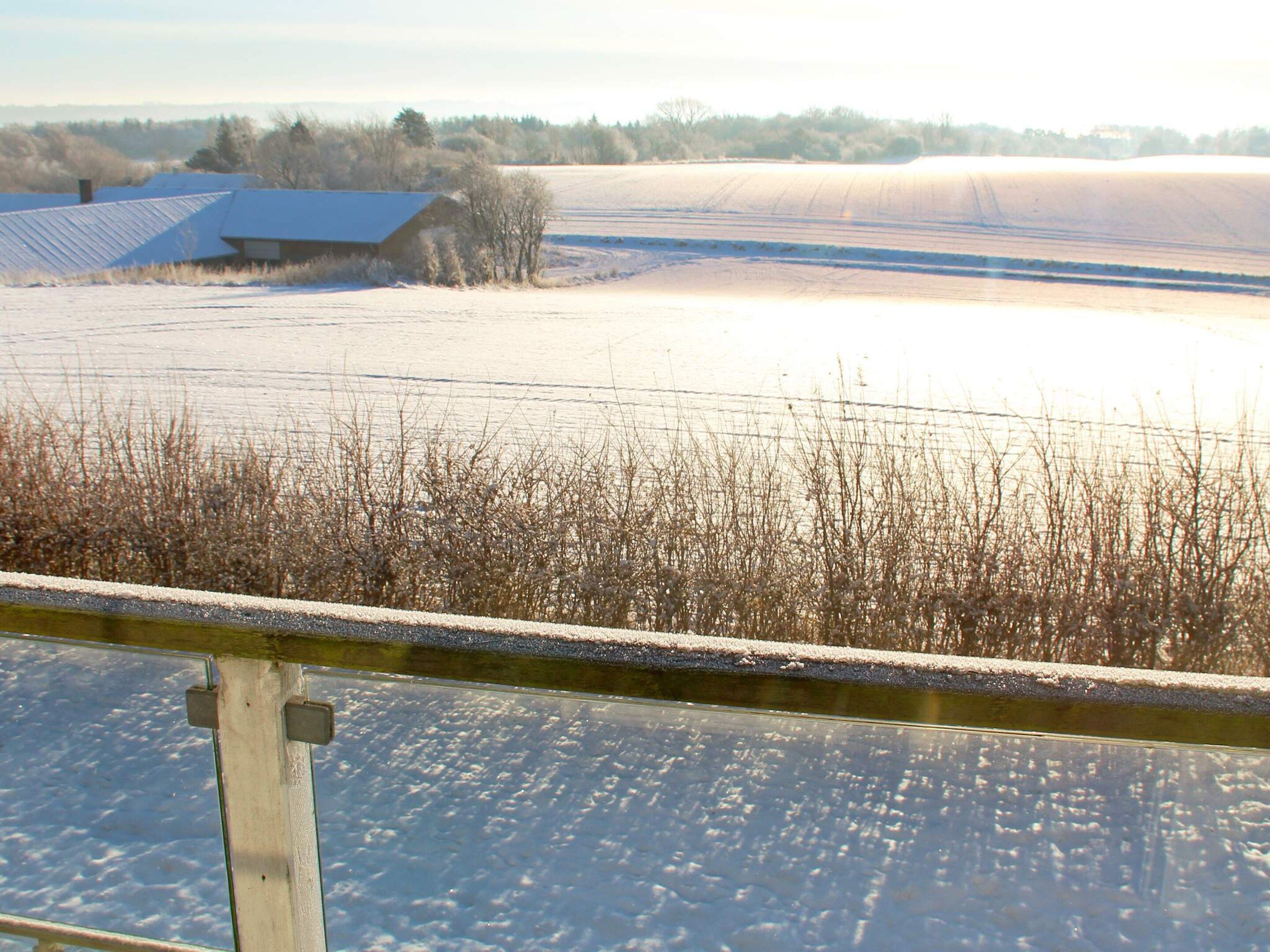 Paisatge nevat amb una granja i camps.