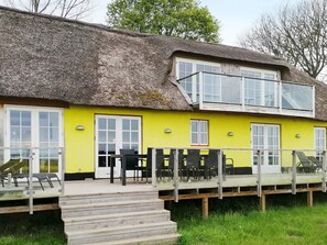A two-story building with a thatched roof and a bright yellow exterior. - 14 Person Holiday Home in Havndal (Havndal)