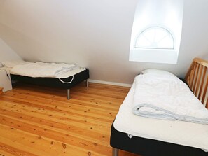 A small, single-room with two beds, a window, and wooden flooring. - 14 Person Holiday Home in Havndal (Havndal)