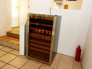 Un horno de acero inoxidable con puerta de vidrio, situado en una zona de cocina con suelo de baldosas y pared blanca.