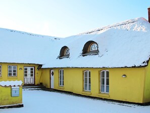 A yellow building with a snow-covered roof and multiple windows. - 14 Person Holiday Home in Havndal (Havndal)