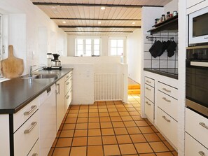 A kitchen with white cabinets, a black countertop, a tiled floor, and a window with a view.