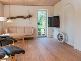 En stue med sofa, bord, fjernsyn og en lænestol.