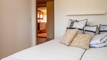 Un dormitorio con cama, almohadas y vista al baño.