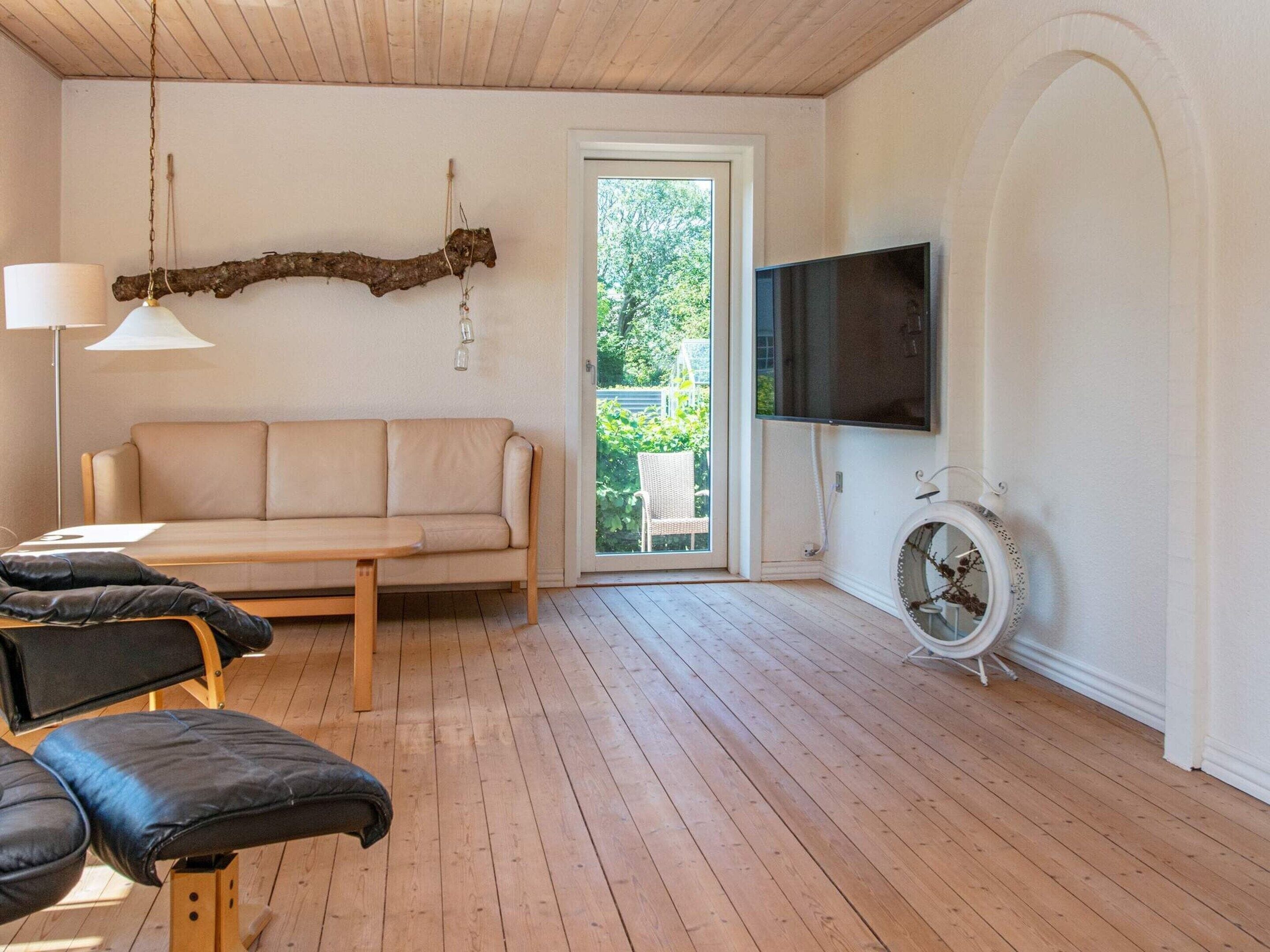 Una sala de estar con un sofá, un televisor, una lámpara y un sillón.